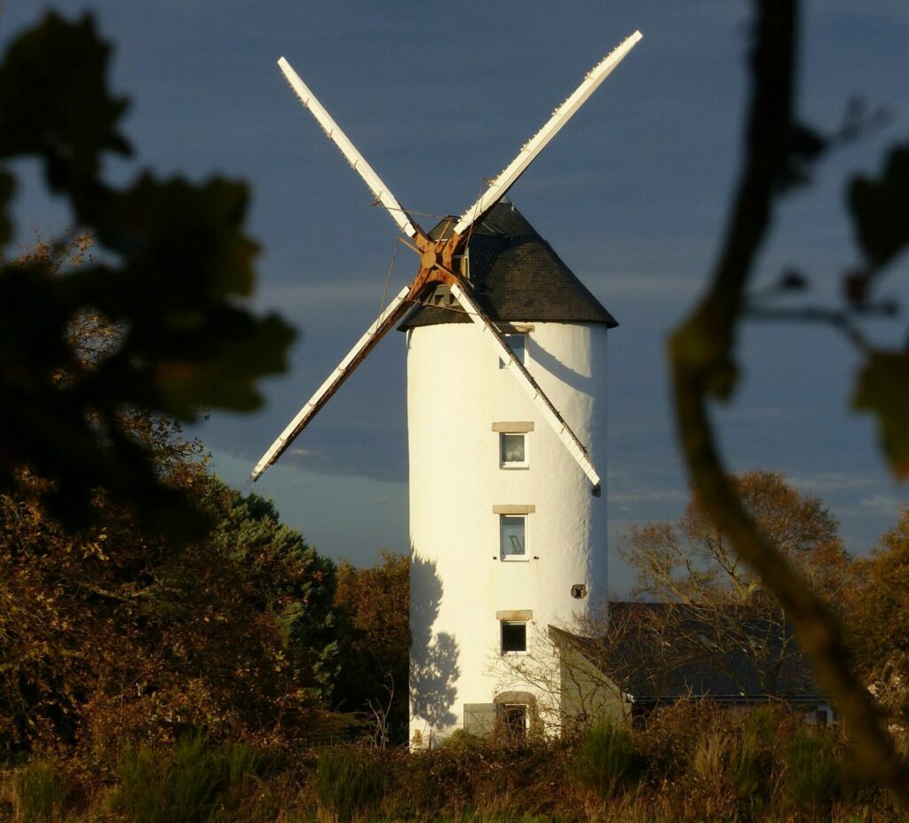 Moulin de la Bicane old traditional windmill located on grassy field against blue sky in countryside